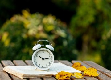 Alarm clock and a book on a table in an autumn garden